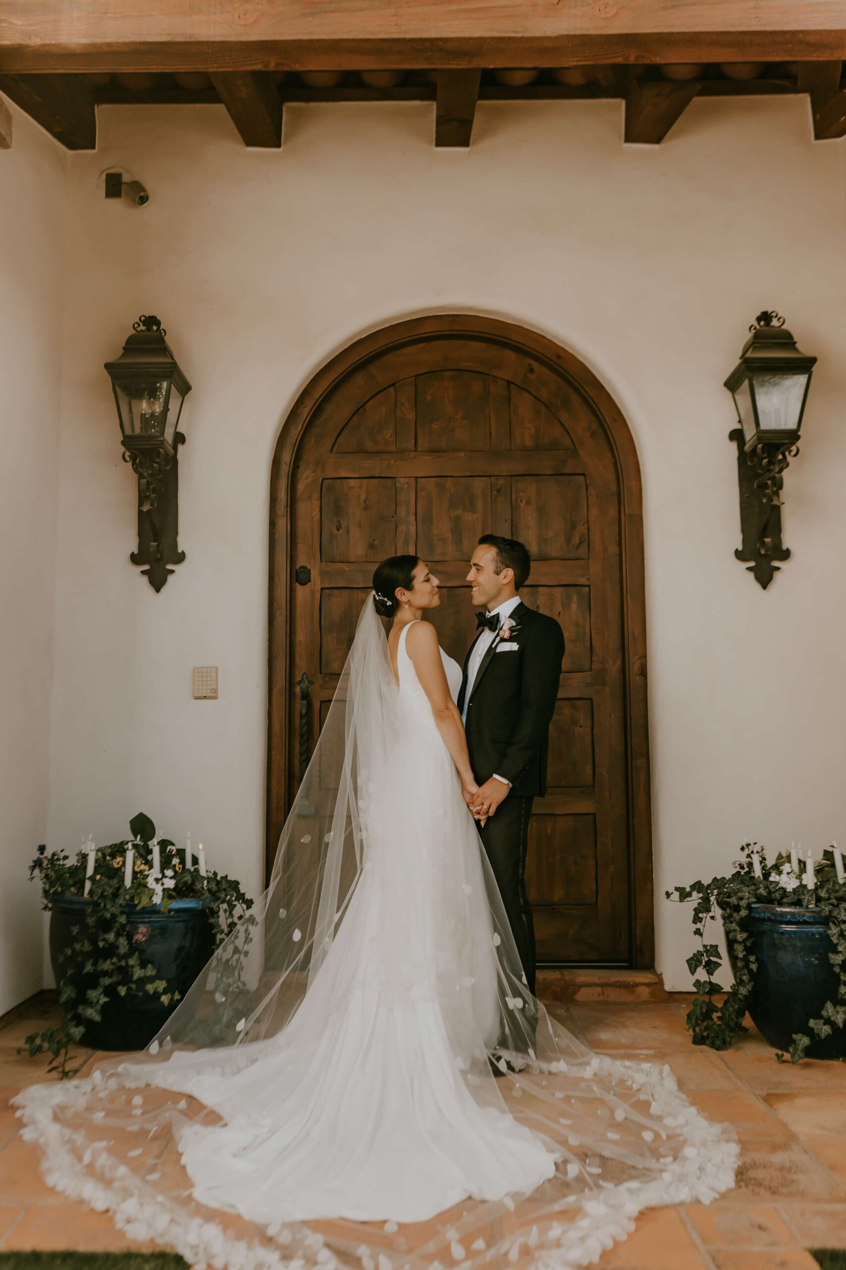 Bride and groom hold hands standing in front of their front door